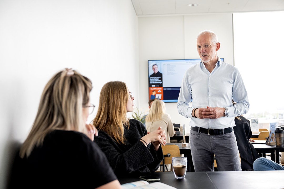 Underviser, der står og snakker med en gruppe studerende