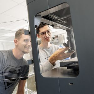 Foto af 2 drenge der står med en 3d-printer