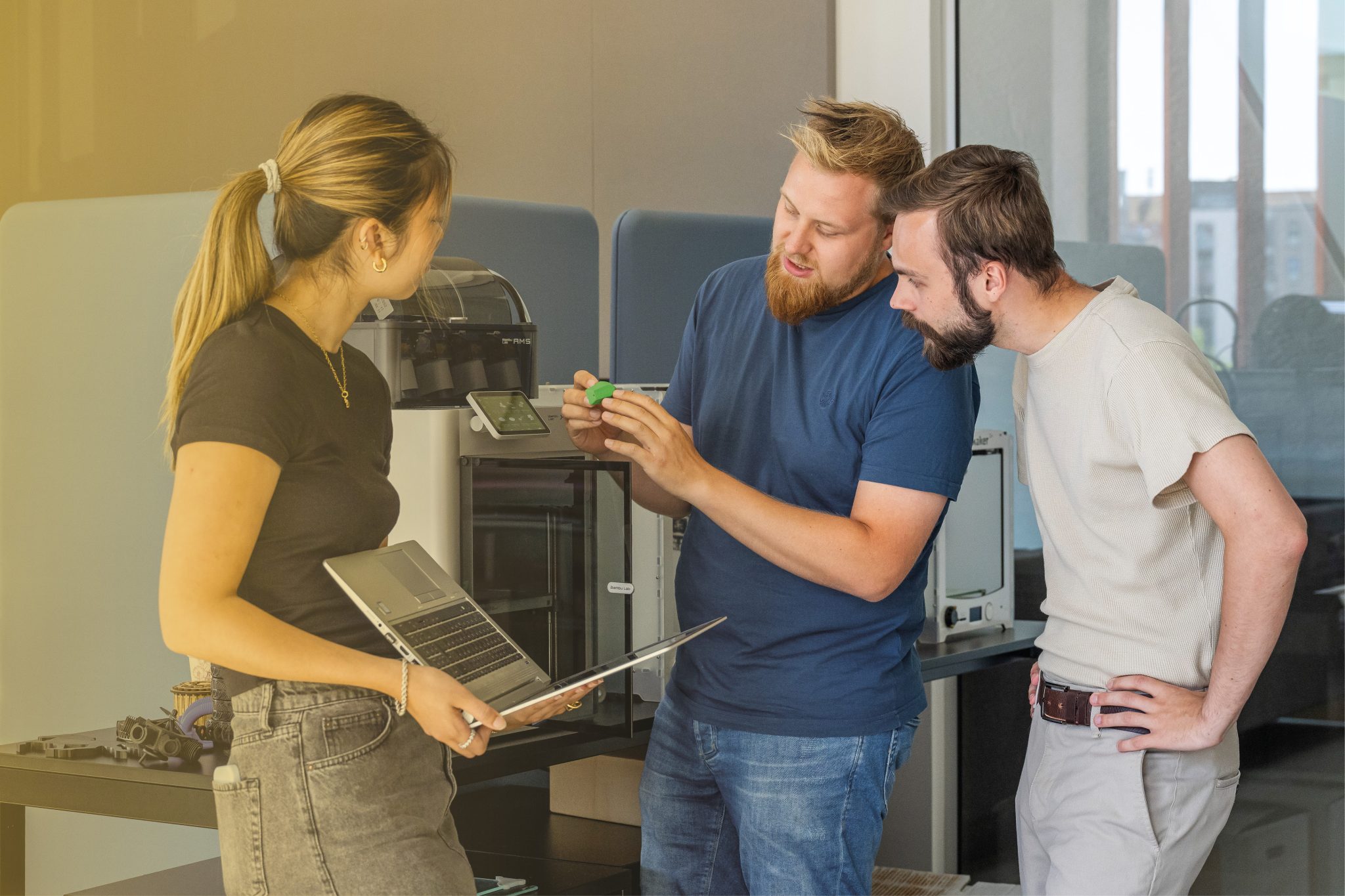 Tre studerende der står foran en 3D-printer.