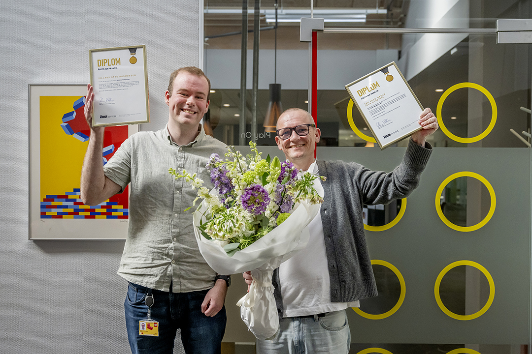 Foto af Villads og sin Chef søren, med diplomer og blomster, der jubler